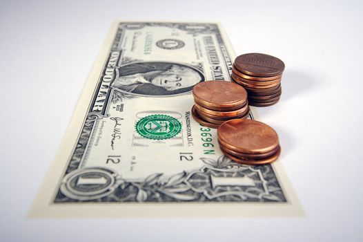 Pennies on the Dollar - one dollar bill with small stacks of pennies on top on a white background.