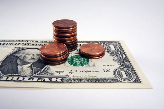 Pennies on the Dollar - one dollar bill with small stacks of pennies on top on a white background.