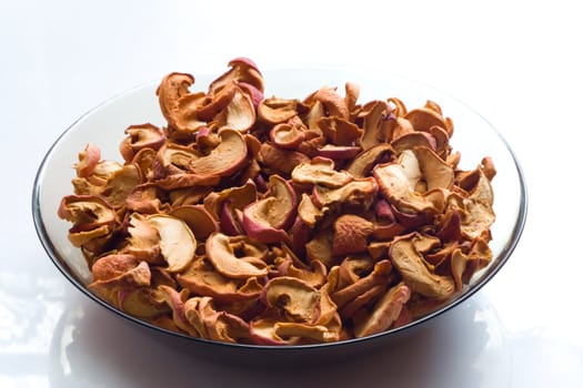 dry slices of apple on a glass plate on white background