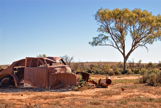 an old car lays rusting in the desert