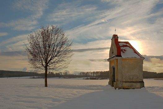 chapel and tree in winter, blue sky with sun and white cloud