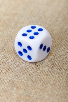 One dice on the surface of brown canvas
