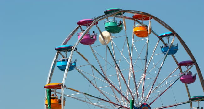 Ferris wheel ride at amusement park, colorful against a clear blue sky