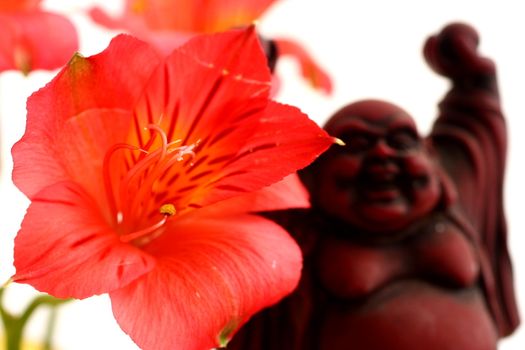 Red Buddha statue with red Peruvian lilies
