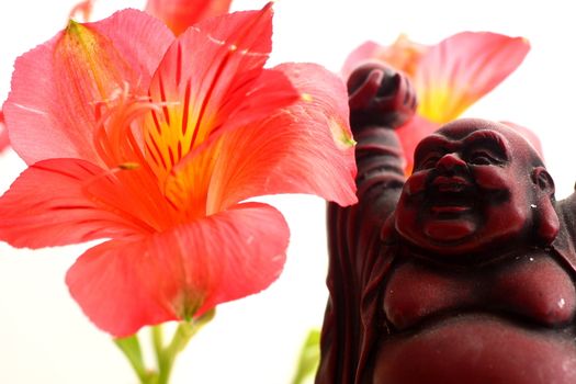 Red Buddha statue with red Peruvian lilies