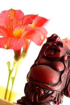 Red Buddha statue with red Peruvian lilies