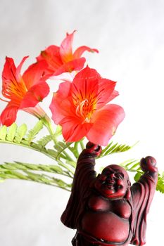 Red Buddha statue with red Peruvian lilies