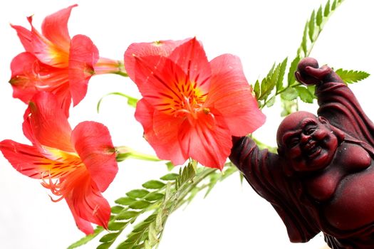 Red Buddha statue with red Peruvian lilies