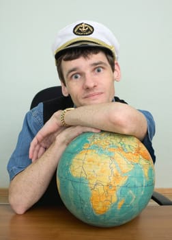 A young man in a captain's cap with a globe