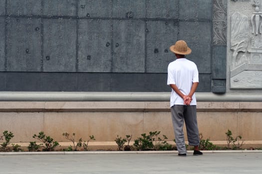 Chinese man reading a text carved on stone