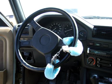 Fluffy handcuffs on a rudder of the car