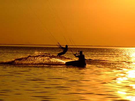 Silhouette of a two kitesurf on a gulf on a sunset