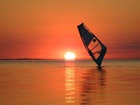 Silhouette of a windsurfer on waves of a gulf on a sunset 1