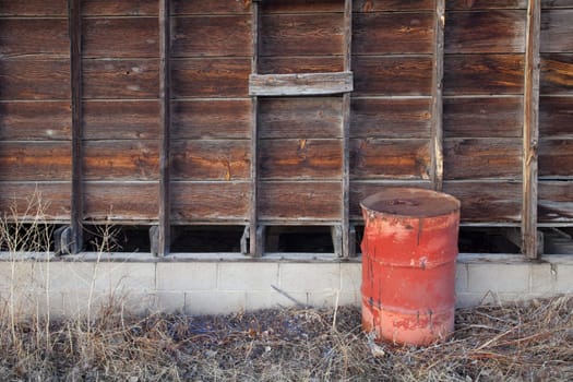 old rusty oil barrel and weathered wooden barn wall