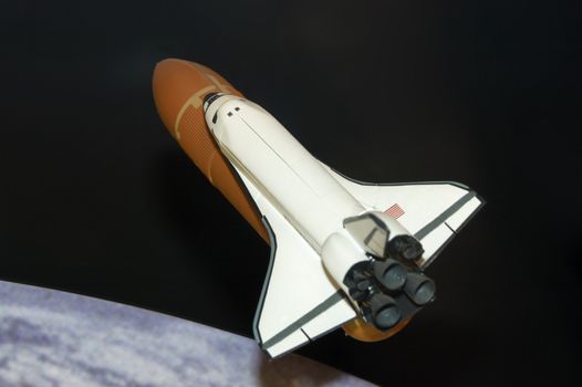 A modle of the space shuttle with the earth in the background