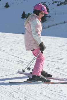 Young girl snow-plows her way down the ski slope.