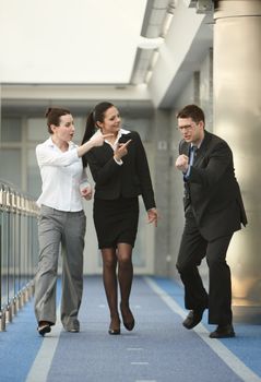 Business portrait of tree persons - young man and two women happy from success on modern office corridor
