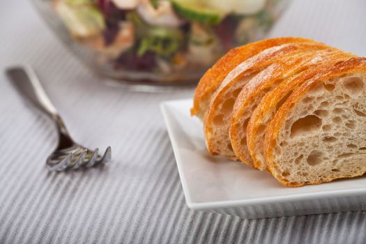 closeup of a slices of baguette bread with a salad as background