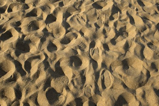 Many footprints in the sand on the beach.