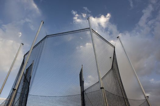 protective cage for a hammer or ball throw competition against cloudy sky