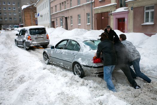 RIGA - FEBRUARY 2: People pushing stuck car in snowy street after heavy snowfall in Riga, Latvia, February 2, 2010 It is extremely cold and snowy winter in Europe this year.