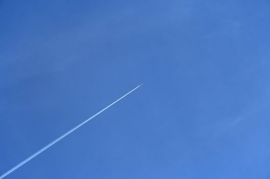 Trace of a jet airplane going up in the blue sky.