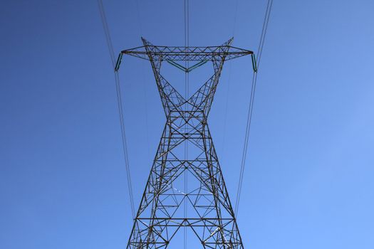 Top of the big high voltage electricity pylon against the sky.