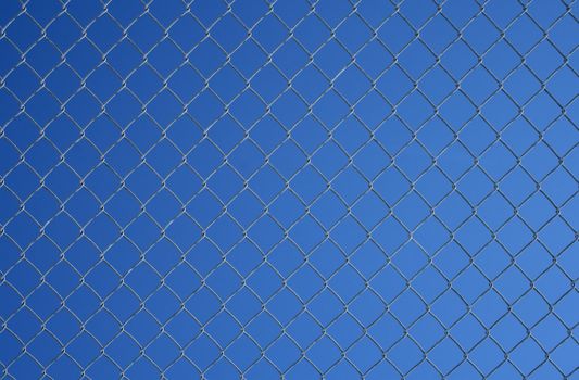 Gray chain link fence on a blue sky background.