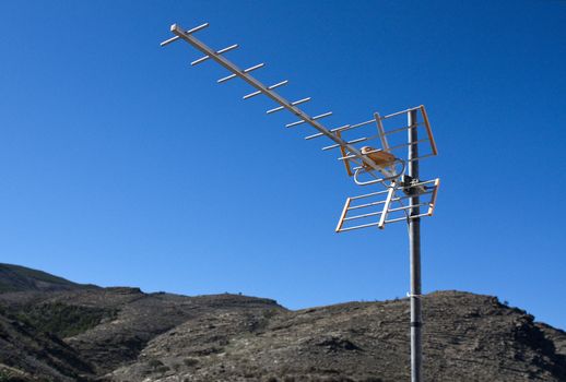 TV aerial with mountains and blue sky as background.