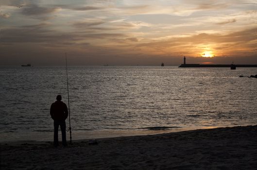 Silhouette of man fishing in the Mediterranean Sea at sunset.