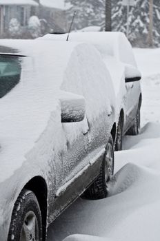 Two cars covered by snow during winter storm.