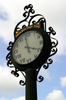 Old street clock with a cloudy sky in the background.
