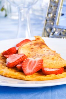 Omelette with sliced fresh strawberries on plate
