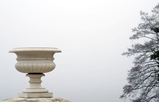 Marble vase. A morning fog above lake. Spring