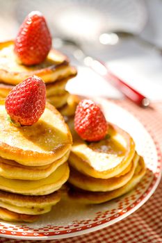 Stack of pancakes with fresh strawberries on plate
