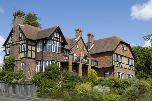 A large detached tudor style house with a blue sky