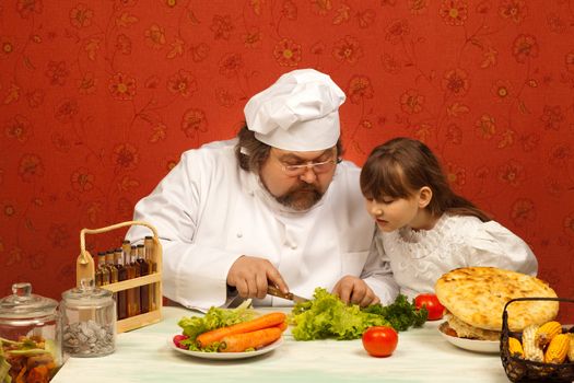 Chef cook teaching little girl to prepare salad