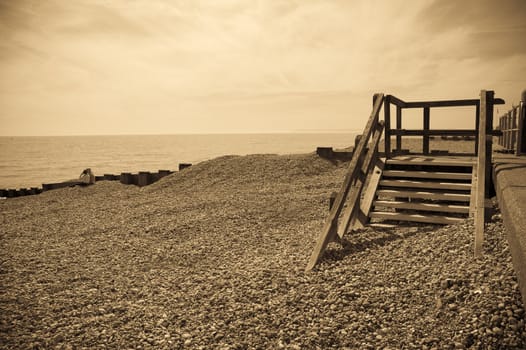 A sepia toned image of a seafront with some old wooden steps