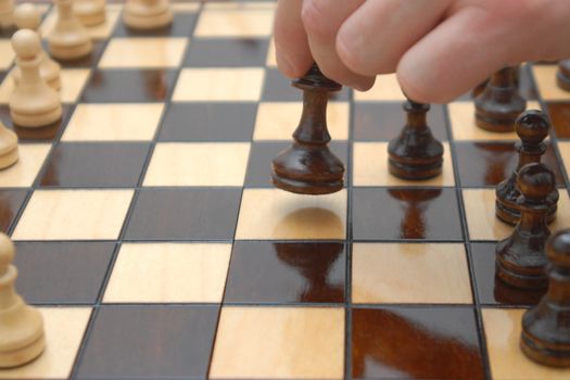 A close-up of the hand playing the chess