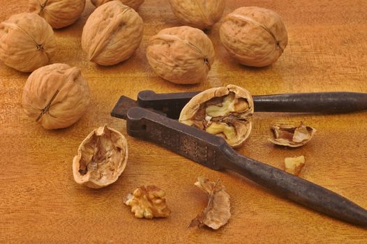 Walnuts with old iron nutcracker on wooden table