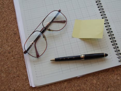 an accounts book with a pen and reading glasses