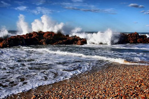 Dramatic shoreline with crashing waves, rocks and pebbles