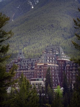 Portrait image of the Fairmont Hotel nestled between mountains and Pine forest in Banf Alberta, Canada, Rocky Mountains, Historic