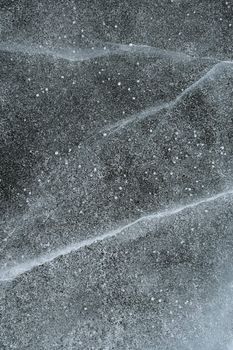 Snowy and icy abstract background. Grainy snow covering cracked ice of a frozen river.
