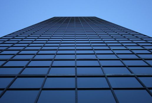 Perspective view of a blue-windowed skyscraper, directly from below.