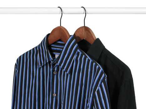 Black and blue shirts on hangers on a rack, on white background.