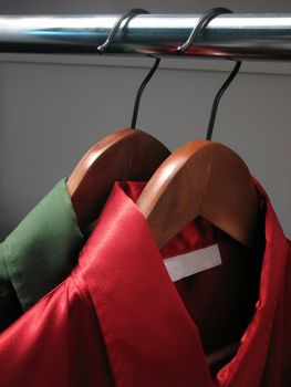 Stylish green and red shirts with an empty label, on wooden hangers in a closet.