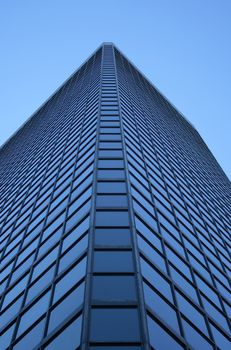 Angle view of a blue glass-windowed skyscraper.