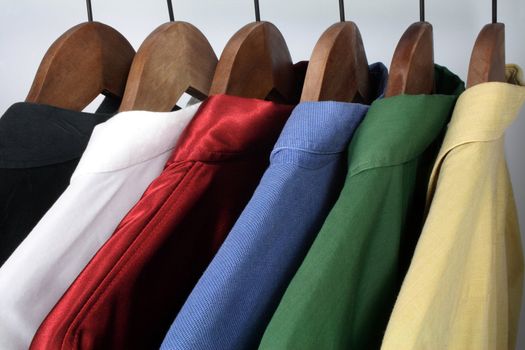 Man's clothing: choice of stylish colorful shirts on wooden hangers.