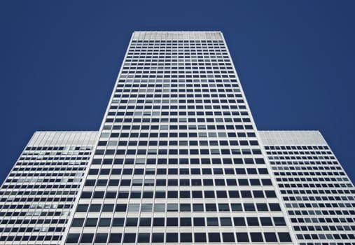 Three-part symmetrical white office building against the blue sky.